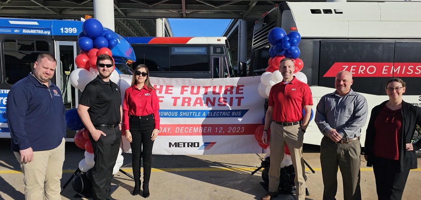 people standing in front of bus with sign and balloons