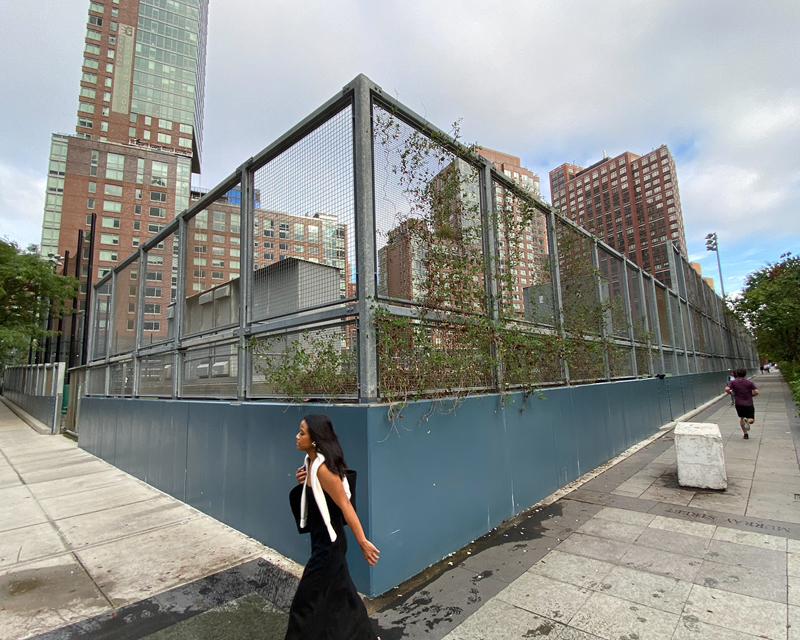 Pedestrians pass by the Battery Park fields