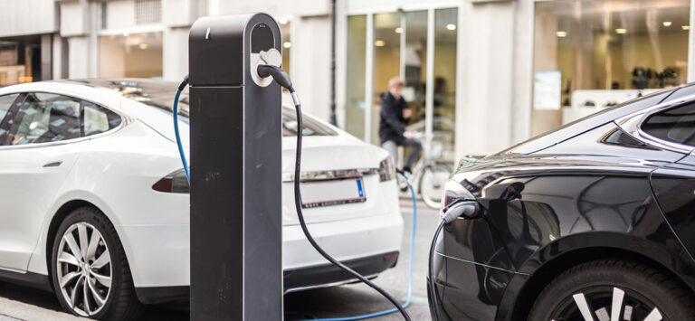 Cars charge at a street-side EV charger.