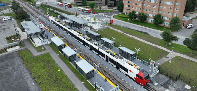 Aerial view of Ottawa light rail train passing through station on new O-Train South service.