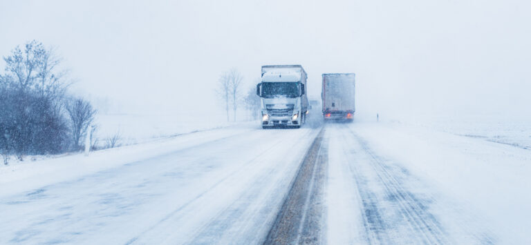 Freight trucks on the road in a snow storm.