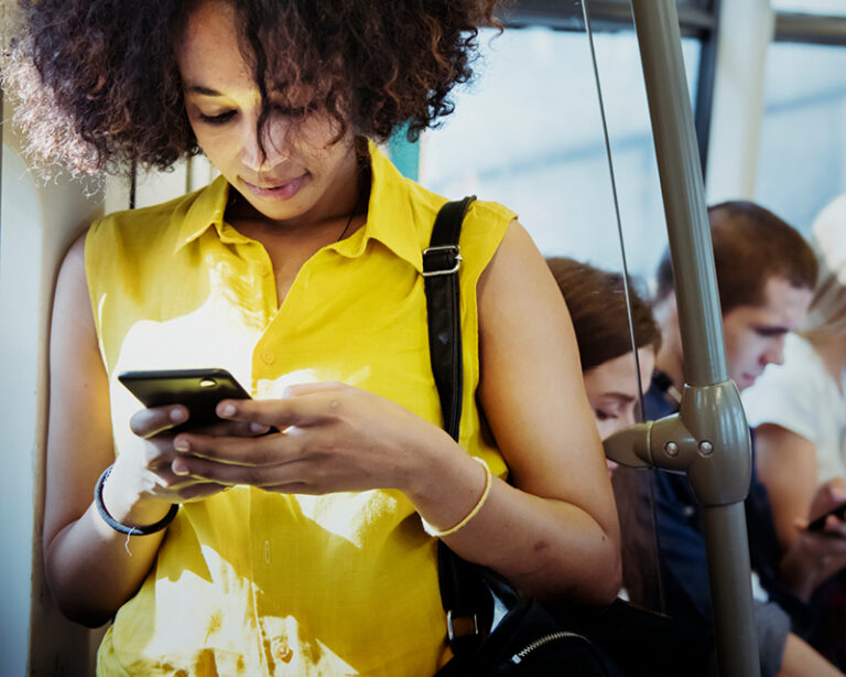 A woman looks at her phone while riding the subway