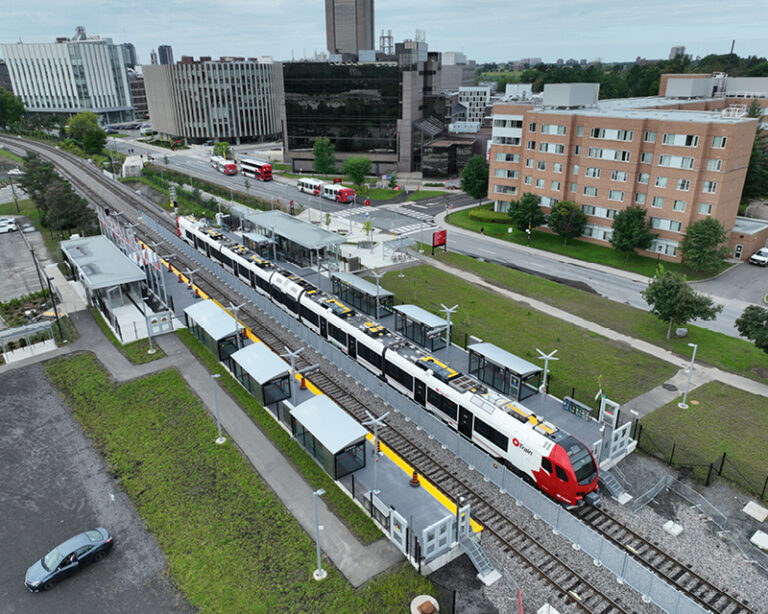 Aerial view of Ottawa light rail train passing through station on new O-Train South service.