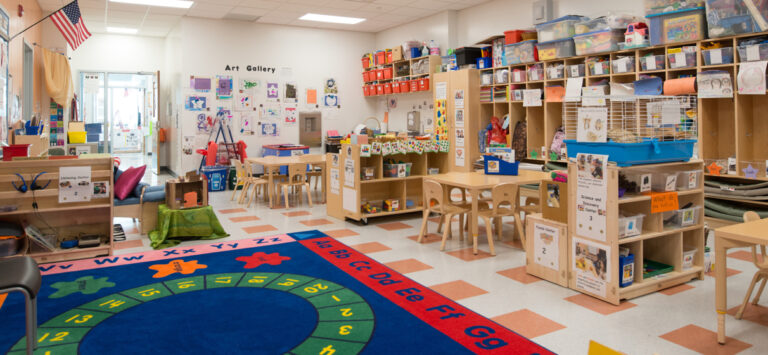 Elementary school classroom with tables and chairs, colorful carpet