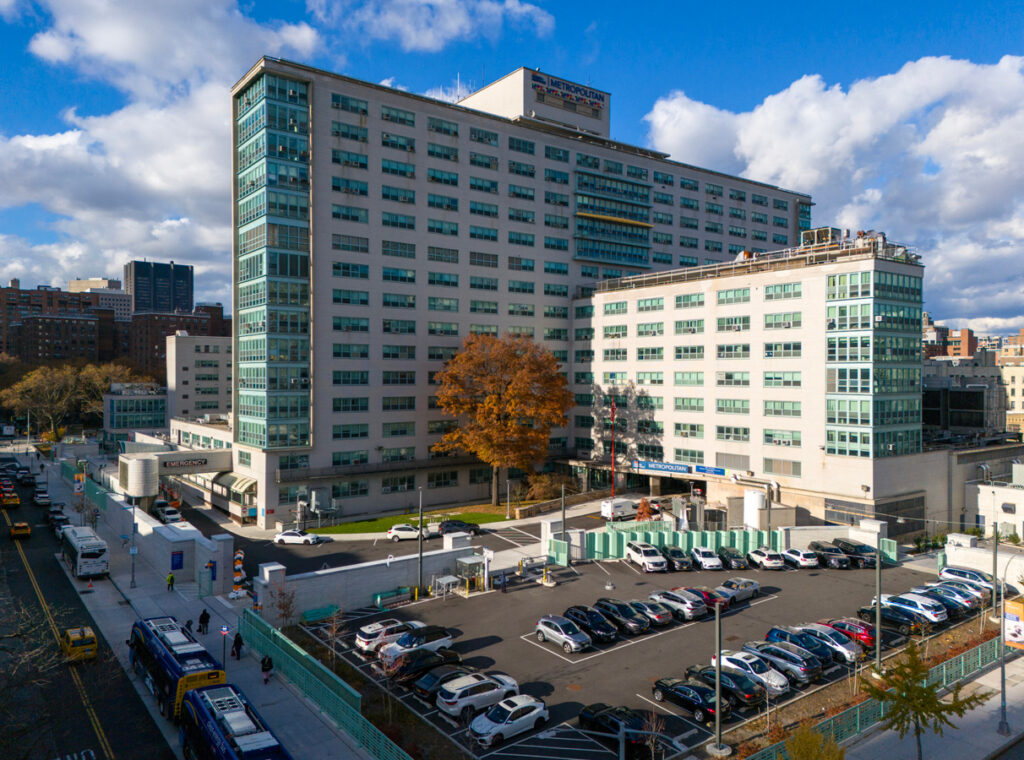 The Metropolitan Hospital building in New York City with a parking lot and floodwall depicted
