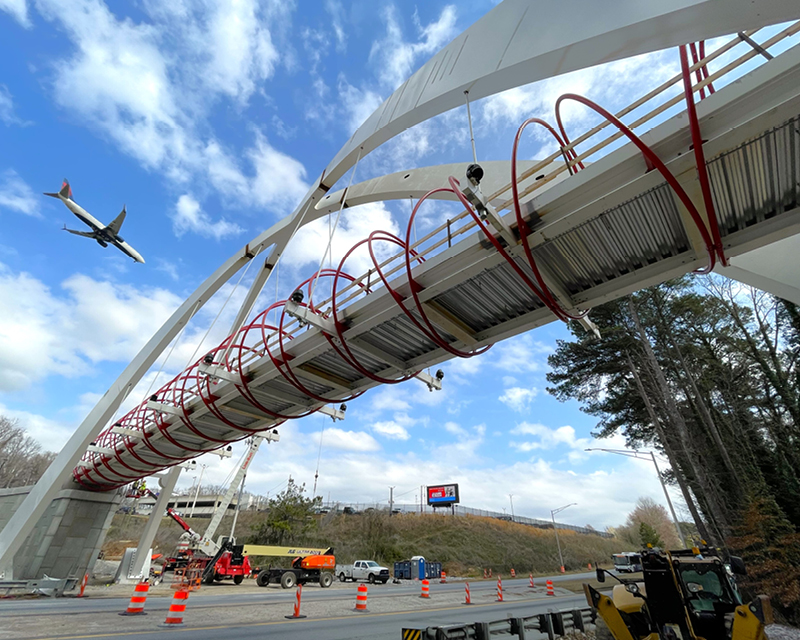 A plane heading to Hartsfield-Jackson Atlanta International Airport passes over the Global Gateway Connector Bridge.
