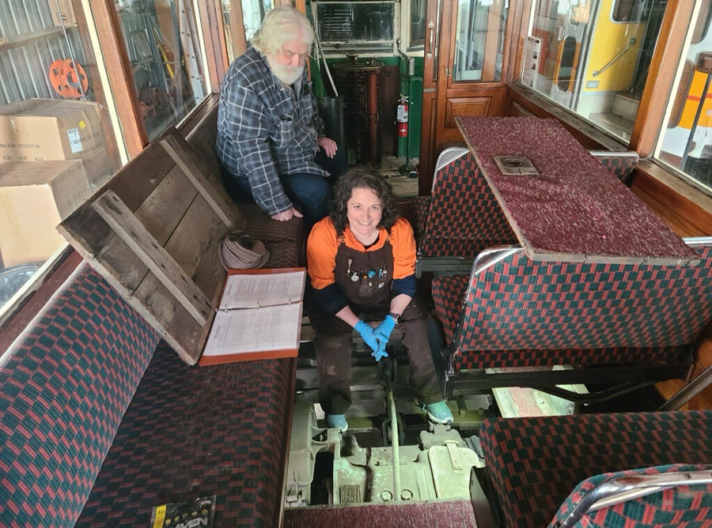 Michelle Veri (sitting) with a colleague at the Oregon Electrical Historical Society inside one of the museum’s vintage trolleys during a repair.