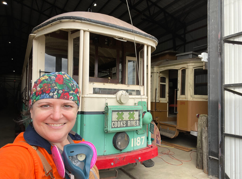 Michelle Veri, in construction attire, in front of a 112-year-old tramcar originally from Sydney Australia that’s now operational for the Oregon Electric Railway Historical Society.