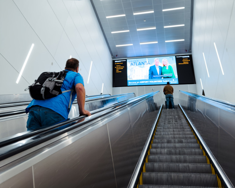 Passengers view the announcements screen while riding the escalator at Hartsfield-Jackson Atlanta International Airport.