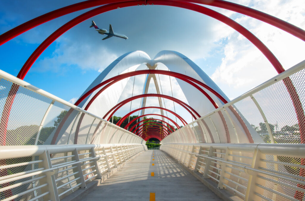Ground-level view of Global Gateway Connector Bridge showcasing the pedestrian walkway from inside the steel arches.