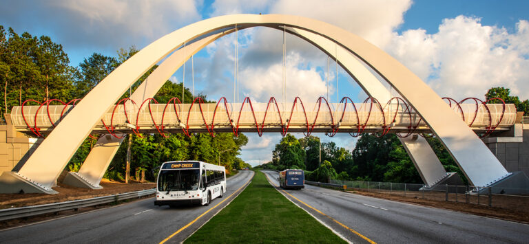 Buses pass under the Global Gateway Connector Bridge.