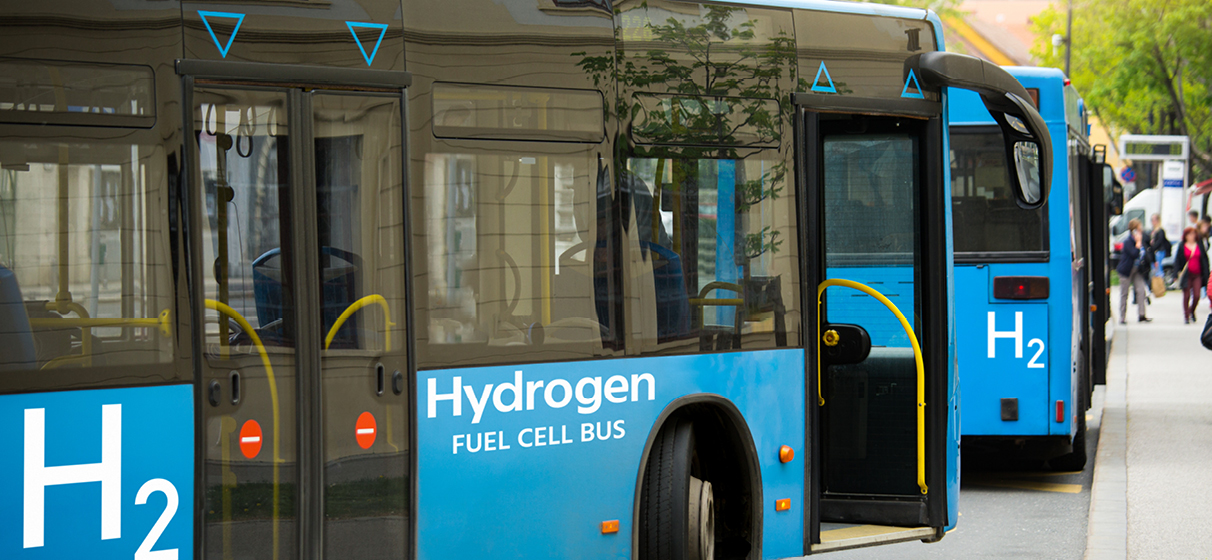 A blue transit bus is parked and the words "hydrogen fuel cell bus" are written on the side of the vehicle.