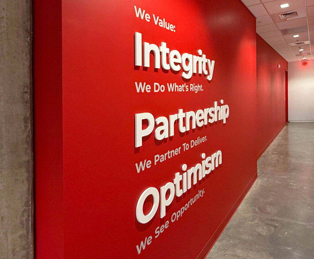 STV's values (Integrity, Partnership, Optimism) displayed on a red wall in the new Raleigh office.