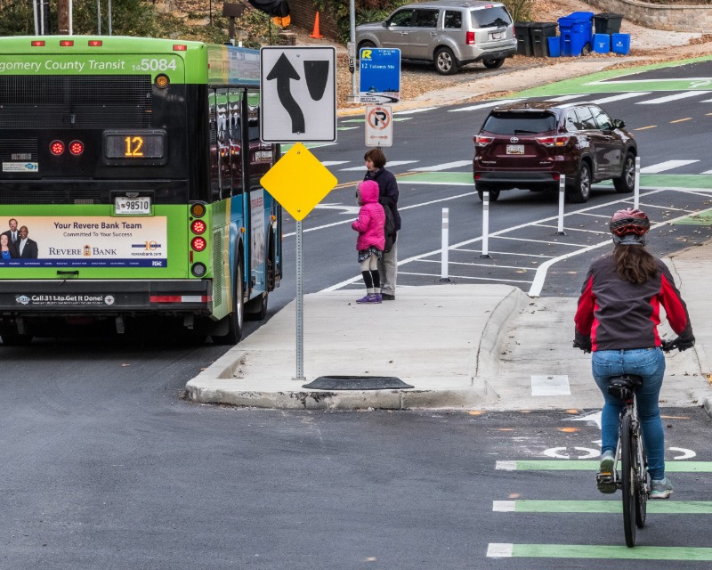 A Flash BRT vehicle in revenue service in Montgomery County, Maryland with pedestrian and cyclists using anciliary roads and paths