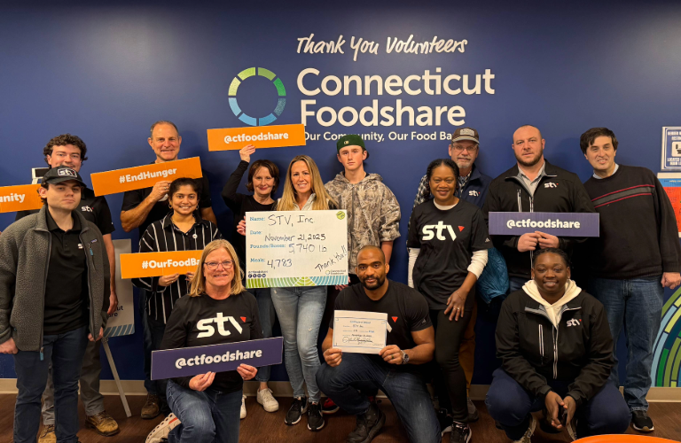 STV's Connecticut team poses in front of a sign fo Connecticut Foodshare, following the team's successful food drive.