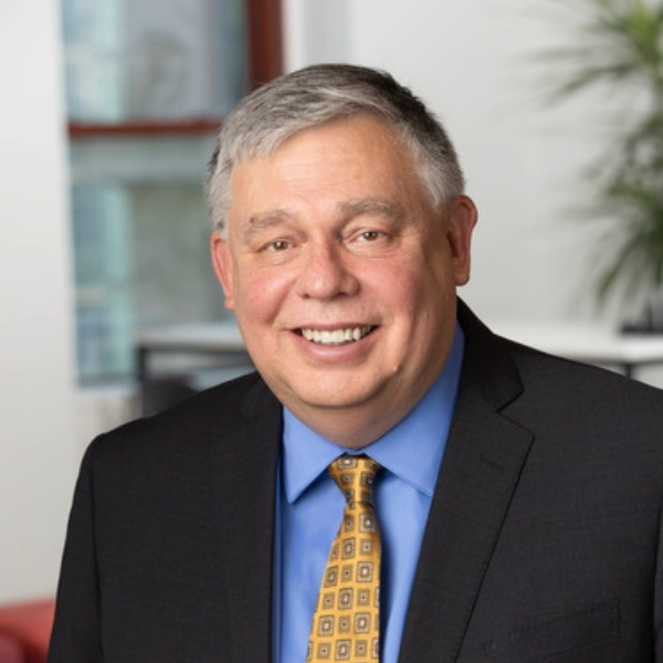 Headshot of businessman in black suit, blue shirt and yellow tie