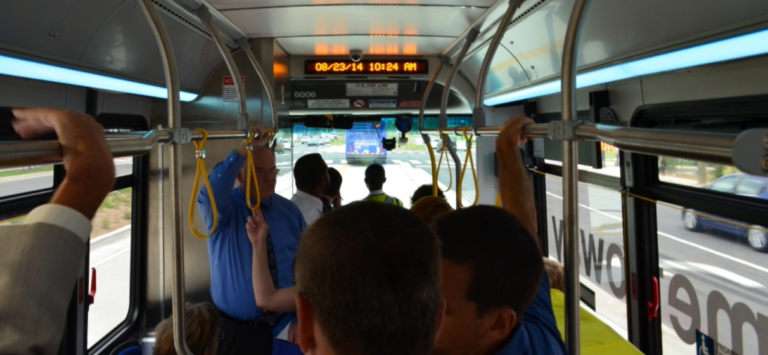Interior of bus riders holding onto rails