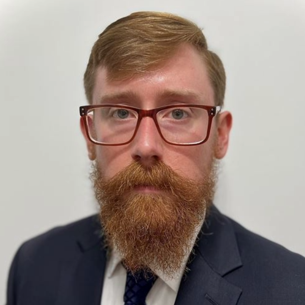 Headshot of man with red hair and beard with glasses