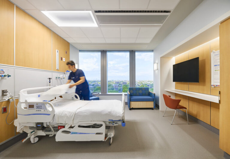 hospital worker in scrubs making a hospital bed