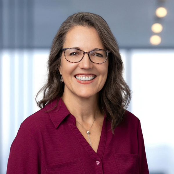 Headshot of woman with brown hair, glasses and red top