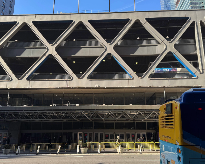 View of the front of the Midtown Bus Terminal in New York City with a New York City Bus in the lower right side of the frame.