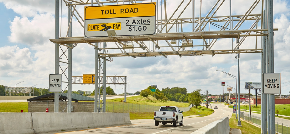 Side view of toll road during day with sign for toll payment on highway