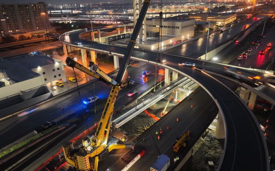 Night shot of construction crane laying a beam into place for construction of the International Parkway at DFW Airport in Texas.