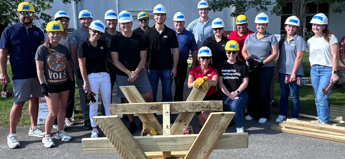 STV's Franklin, Tennessee team poses in front of constructed picnic tables during a Habitat for Humanity ReStore volunteer event.