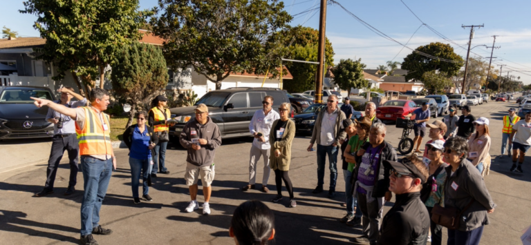 Man in construction vest giving community walk to circle of residents outdoors