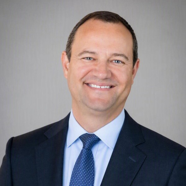 Headshot of man in black suit with blue tie and shirt