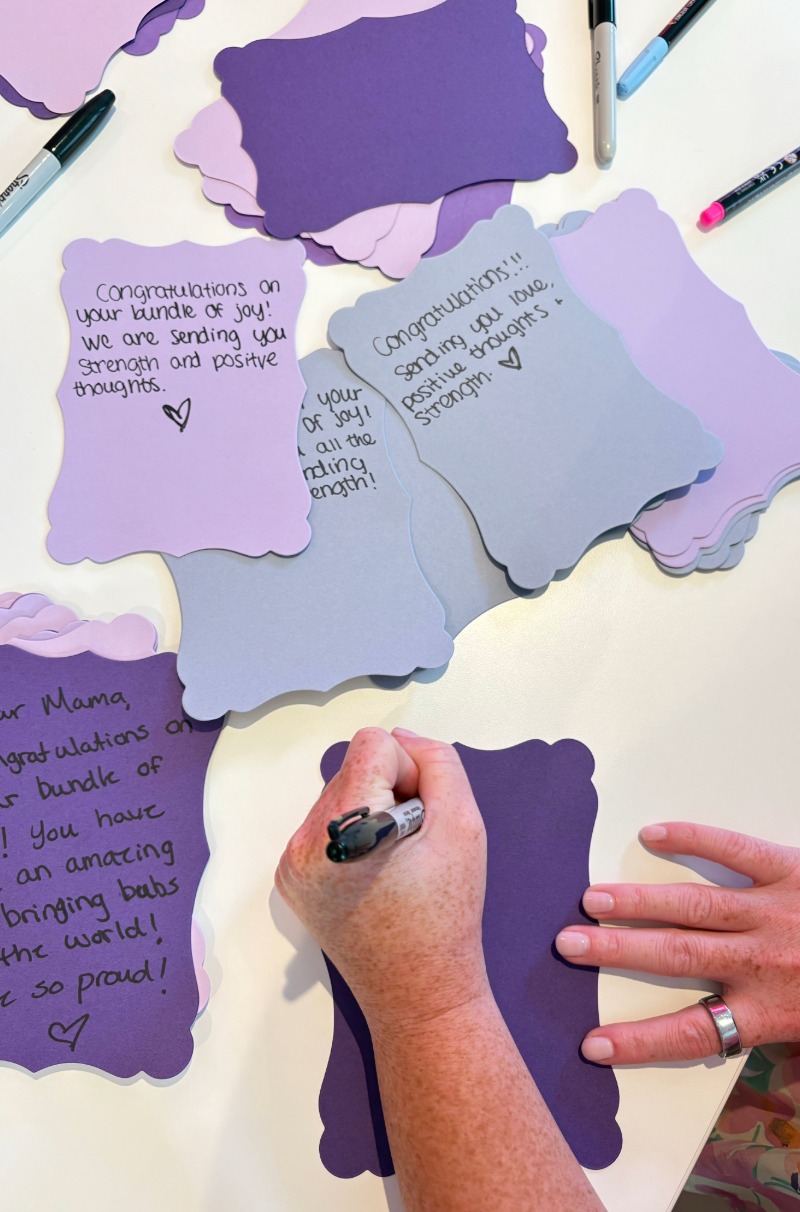 A hand writes notes of encouragement for March of Dimes fundraiser.