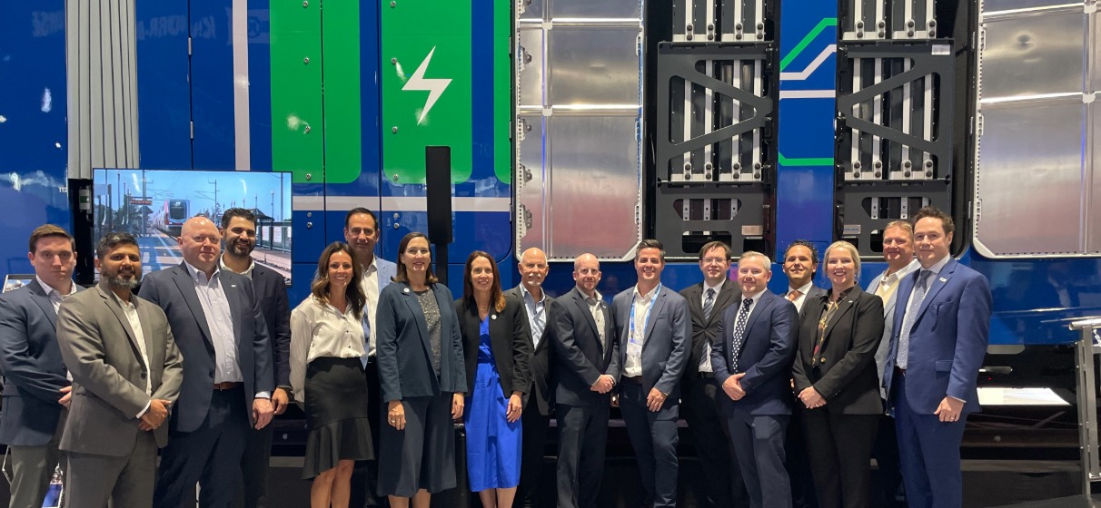 Group photo of people posing in front of blue and green metra BEMU