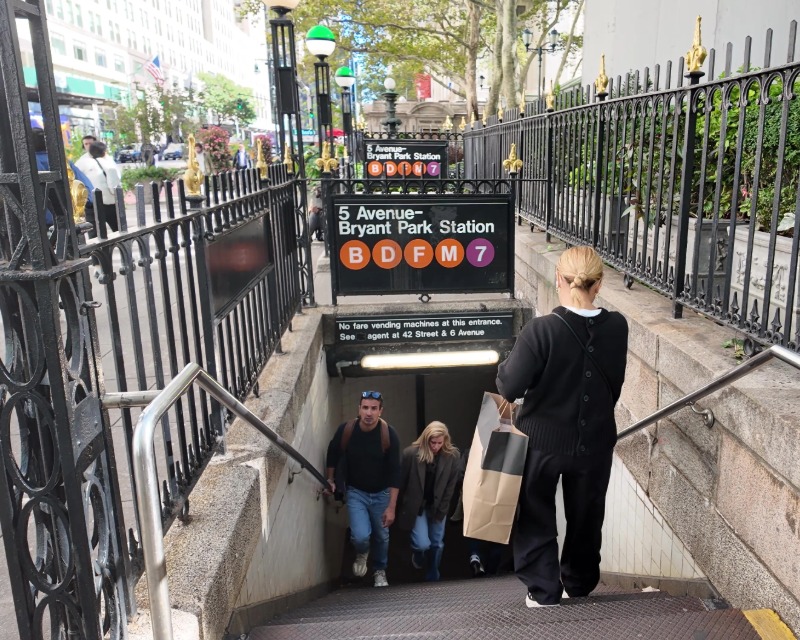 Commuters go up and down staircase at street level at 42 St-Bryant Park Station in New York.