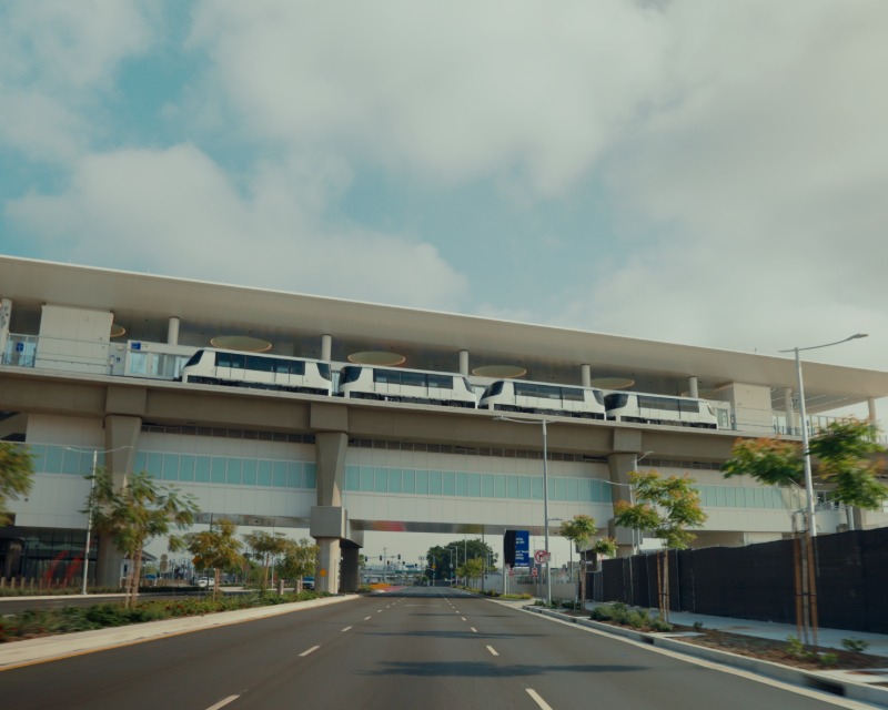 LA Metro train stopped at platform at LAX/Metro Transit Center with roadway below.